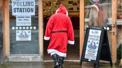 PA Media Santa goes to vote in Dunster Tithe Barn near Minehead, Somerset