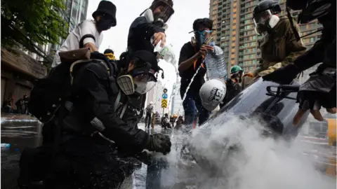 Getty Images Protesters put out a tear gas grenade at Din Daeng intersection during the demonstration in Thailand, August 2021.