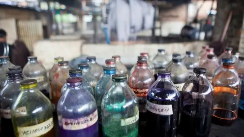 Getty Images A collection of glass bottles containing dyes to be used for staining wool at a textile factory in Nepal