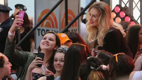 Getty Images Perrie Edwards poses with fans in America