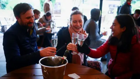 Reuters People toasting in a pub in London on 12 April