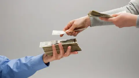 Getty Images Hands exchanging money.