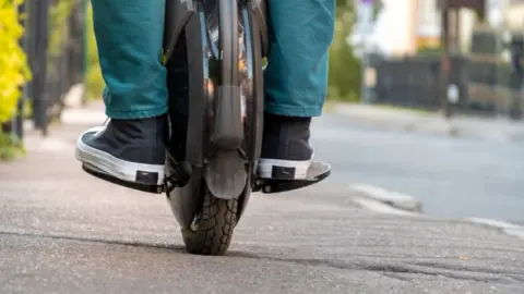 Getty Images Man riding an electric unicycle on pavement