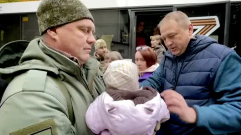 Igor Kastyukevich Igor Kastyukevich (left) with children being loaded onto a bus