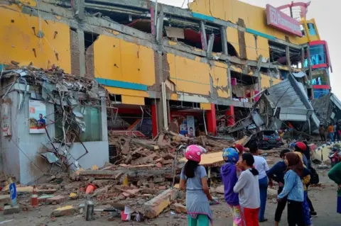 Antara Foto/Rolex Malaha via Reuters People stand in front of a damaged shopping mall after an earthquake hit the city of Palu, on Indonesia's Sulawesi Island