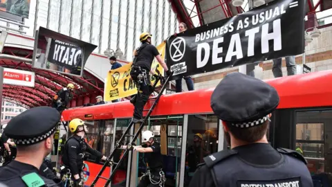 AFP/Getty Police prepare to remove climate change activists on the roof of a DLR train at Canary Wharf station