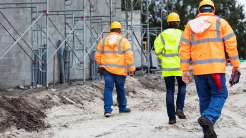 Getty Images The backs of three builders as they walk away