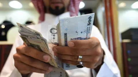 Getty Images A man counts Saudi riyal banknotes in Riyadh.