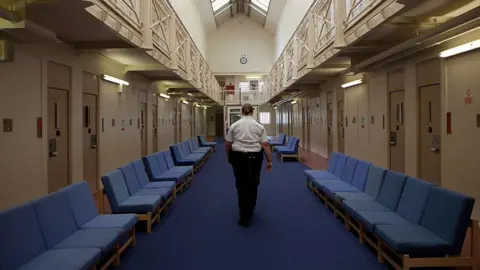 Getty Images A female prison officer walks through the communal area inside HM Prison Styal in Cheshire