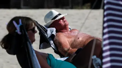 Getty Images man sunbathes on beach in Chichester