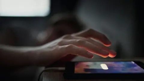 DGLimages Man checking phone on bedside