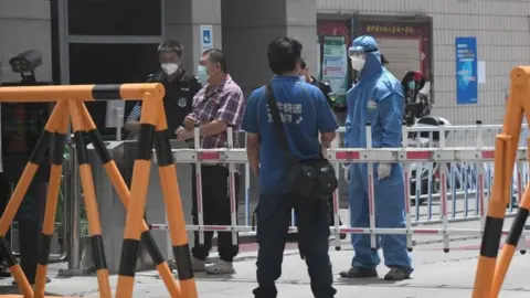 Getty Images Security guards at a residential area under restrictions near Yuquan East Market in Beijing
