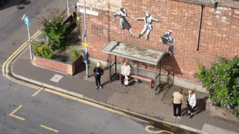 Shaun Whitmore/BBC  Banksy mural above a bus stop in Great Yarmouth.