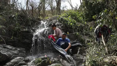 Getty Images A couple washes their clothing in a stream on Sunday