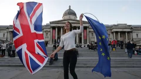 Getty Images A Pro-European Union protester holds Union and European flags in Trafalgar Square