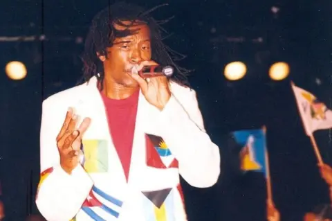 Antigua & Barbuda Festivals Commission King Onyan performs wearing a flag-covered white suit