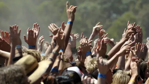 Getty Images People hold their wristbands up at a festival