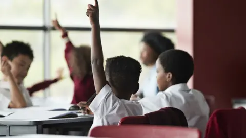 Getty Images Raised hands in classroom