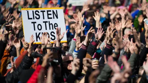 Lindsey Wasson / Getty Images People hold their hands up as directed by musician Brandi Carlile at Seattle Center during the March for Our Lives rally