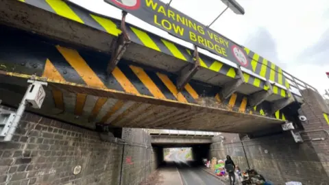 Nick Mann/BBC Items piled up under a bridge in Ely
