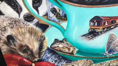 Cindy Powell Close up shot showing some of the detail in the painting, with a hedgehog, badger, frog, snake, butterfly and a teacup with a train on a railway track