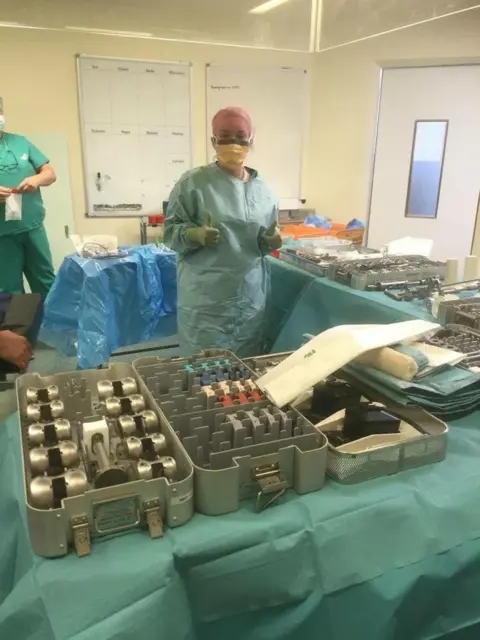 Yoana Peacock Yoana is wearing full green scrubs in an operating theatre, surrounded by utensils used in joint replacements.