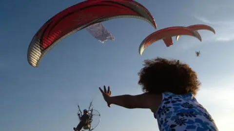 AFP A girl reaches up towards military paragliders in Casablanca, Morocco - Saturday 30 September 2017