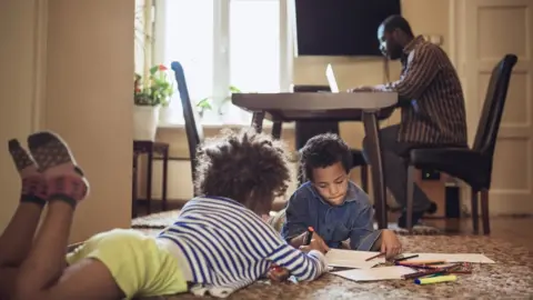 Children colouring while dad works