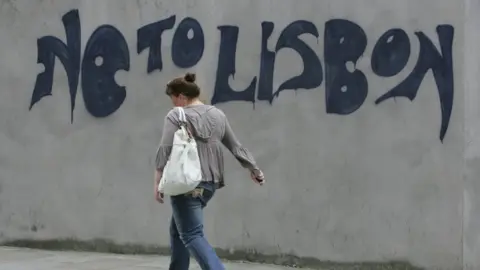 Getty Images A woman walks past graffiti in Dublin, on June 13, 2008.