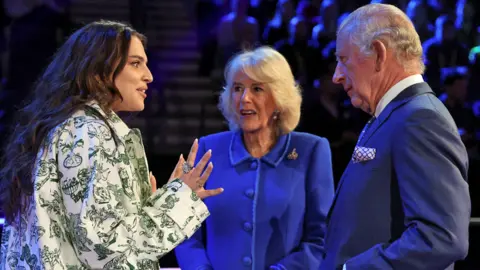 PA Media King Charles III and the Queen Consort meets the UK's Eurovision Song contestant Mae Muller, during a visit to the M and S Bank Arena, the host venue of this year's Eurovision Song Contest, to reveal this year's staging and tour the arena, meeting the creative team and presenters