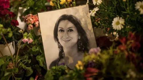 Getty Images Flowers and tributes for Daphne Caruana Galizia left at a monument in Malta in March 2018