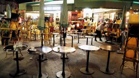 Reuters A staff member prepares to close a restaurant minutes before the late-night curfew in Paris