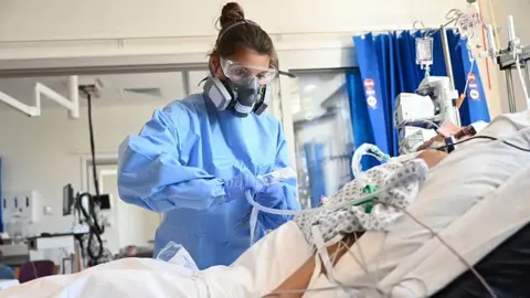 Getty Images Member of clinical staff caring for patient in ICU