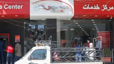 AFP Customers queue outside a shop operated by Syriatel in Damascus, Syria (11 May 2020)