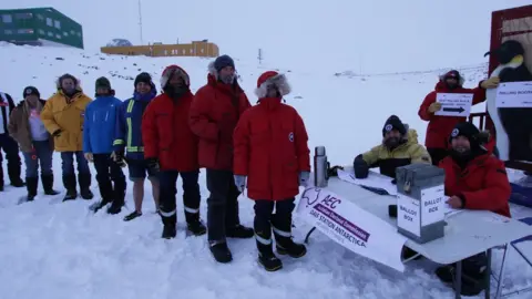 Aaron Stanley/Australian Antarctic Division A group of people queue in the snow to vote at a ballot box outside