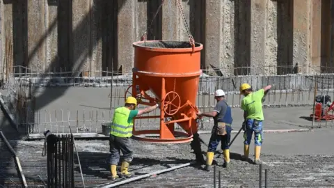 Getty Images Construction workers pour concrete for residential buildings under construction at a large construction site in Munich, southern Germany, May 11, 2022