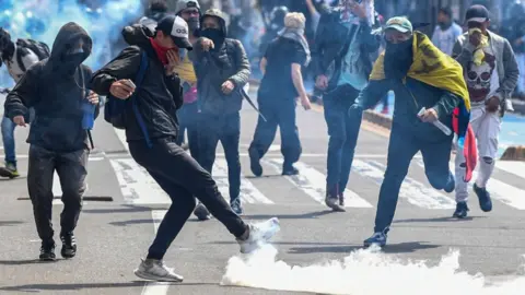 Getty Images Demonstrators confront riot police during a protest against the government in Bogota