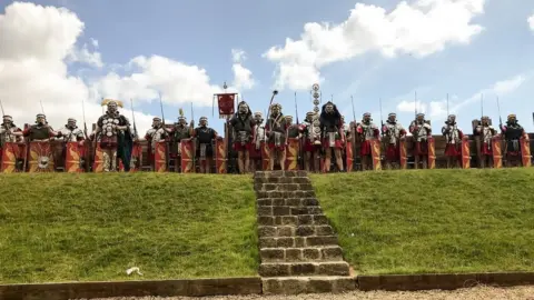Vindolanda Trust Men in Roman military costumes stand in a line