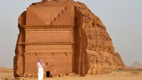 Getty Images Man stands outside of the Qasr al-Farid tomb in Madain Saleh, a UNESCO World Heritage site, near the town of al-Ula in Saudi Arabia