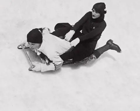 Jacques Henri Lartigue A young man and woman fly sledge down a snow-covered slope
