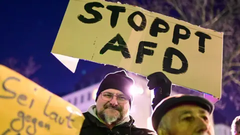 Ina FASSBENDER /AFP A man holds up a placard reading "Stop AFD" during a demonstration against right extremism and the policy of Germany's far-right the Alternative for Germany (AfD) party, on January 16, 2024 in Cologne