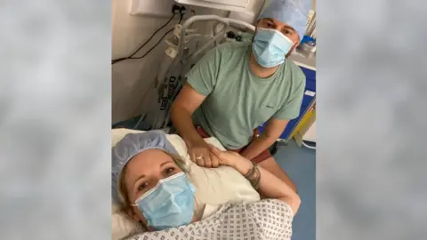 Esther Bathers  A woman and a man holding hands in a hospital bed