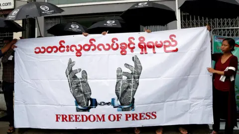 Reuters Journalists hold a banner as they protest against a law they say curbs free speech, at the start of a trial of two journalists who the army is suing for defamation over a satirical article, in Yangon