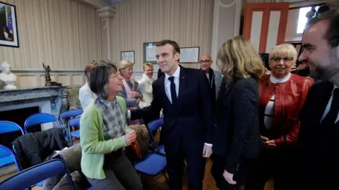 AFP French President Emmanuel Macron (C) arrives to attend the city council at the town hall in Gasny before the launching of the Grand Debate designed to find ways to calm yellow vest protests in France, on January 15, 2019