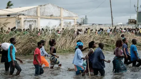 Getty Images People wade through floodwater in Mozambique