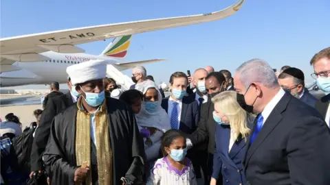 Israel GPO Israeli Prime Minister Benjamin Netanyahu (right) and his wife Sara greet Falash Mura Jews on their arrival at Ben Gurion Airport (03/12/20)