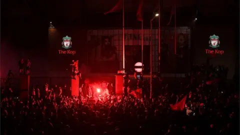 AFP/Getty Images Fans celebrate Liverpool winning the Premier League title outside Anfield stadium