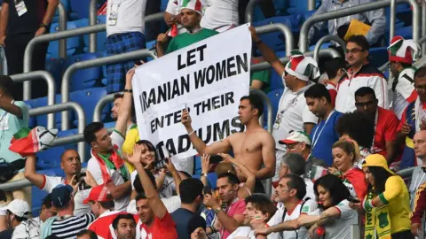 Getty Images Iran's fans hold up a banner reading "Let Iranian women enter theirs stadiums" at 2018 World Cup match between Morocco and Iran at the Saint Petersburg Stadium in Saint Petersburg on June 15, 2018.