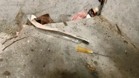 Richard Madden/BBC A hypodermic needle is left in the corner of a staircase alongside dirt and other rubbish