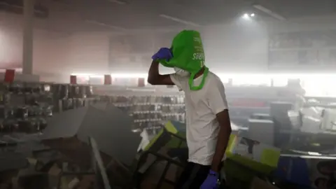 Reuters A man covers his head with a shopping bag inside a damaged office supplies store in Minneapolis